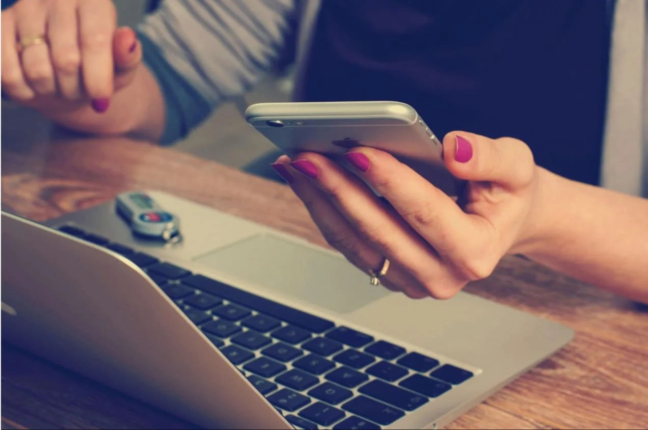 Person looking at their phone in comparison to what's on their computer.