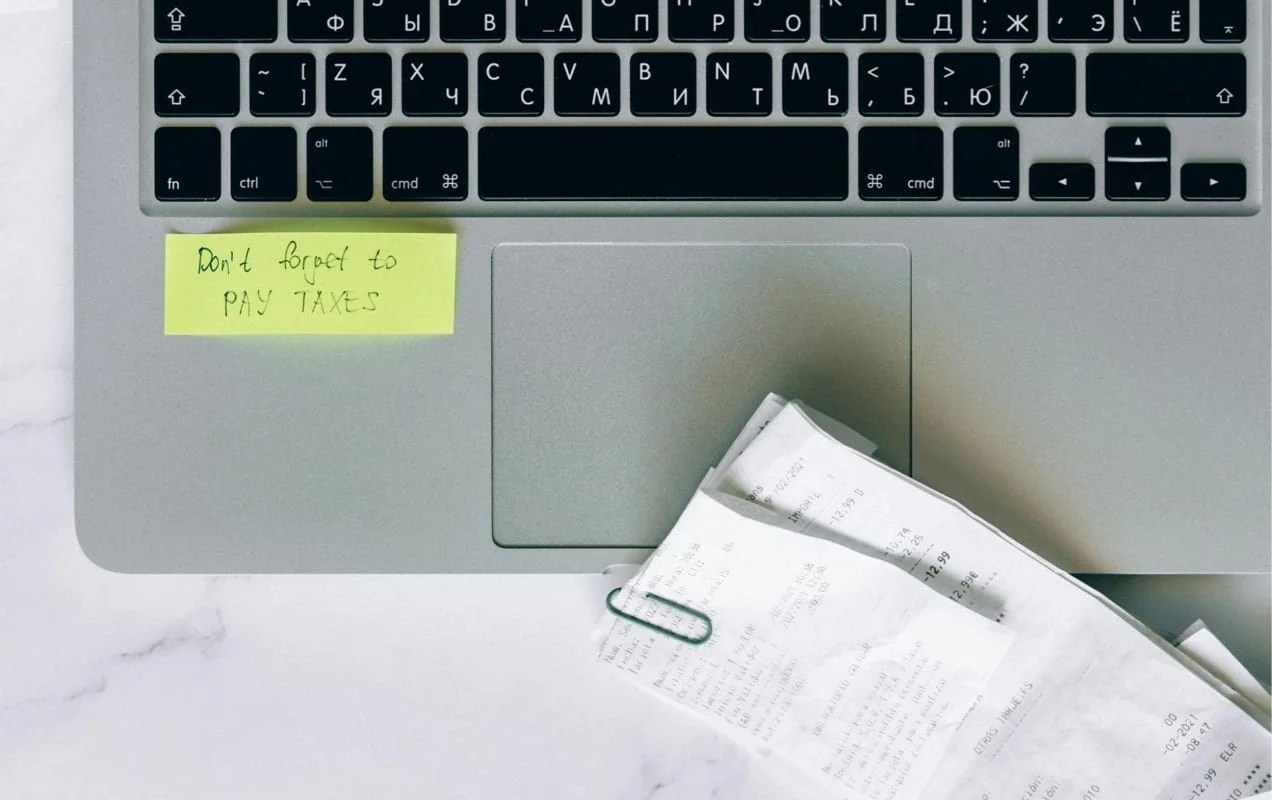 laptop with receipts and a note about paying taxes